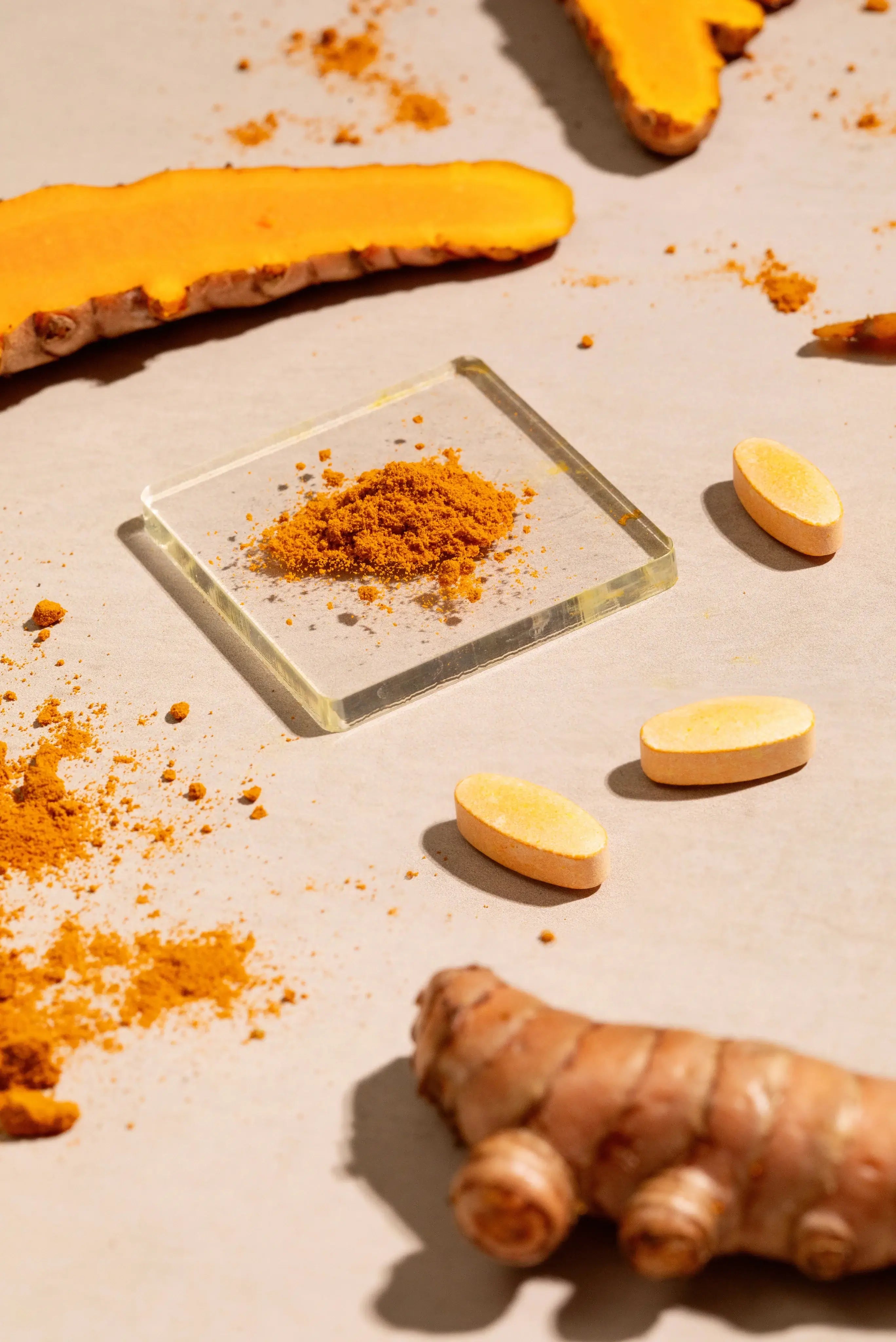 Turmeric root and ground turmeric powder on a light brown surface